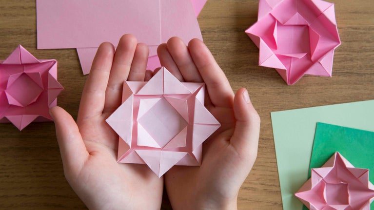 A child holds a folded origami flower